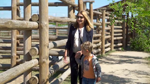 金发母亲和儿子走在动物园的鸟舍附近视频素材