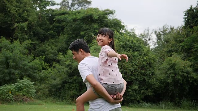 父亲背着女儿在慢镜头中微笑着旋转视频素材