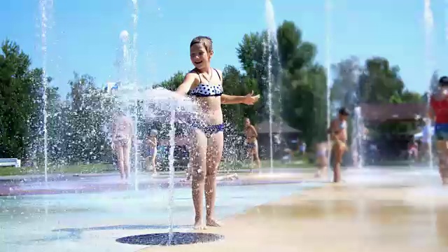 微笑，快乐的8岁女孩在街道城市喷泉，户外，在公园，夏天，在假期炎热的晴天嬉水视频素材