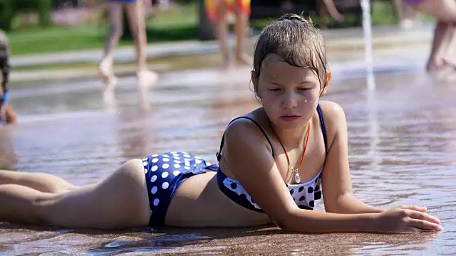 微笑，快乐的8岁女孩在街道城市喷泉，户外，在公园，夏天，在假期炎热的晴天嬉水视频素材