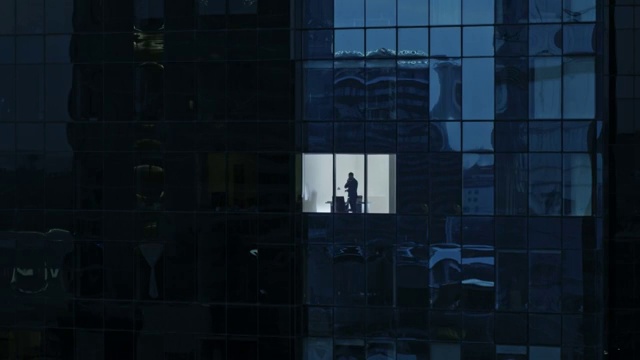 鸟瞰图镜头:从外面到办公大楼，商人使用手机，站在办公室窗户旁。金融商业区摩天大楼的美丽撤退的飞行镜头。视频素材