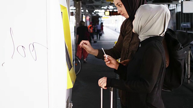 两位女性穆斯林朋友购买公共交通车票(慢镜头)视频素材