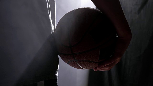 篮球运动员拿着球，站在黑暗的雾气弥漫的房间里视频素材