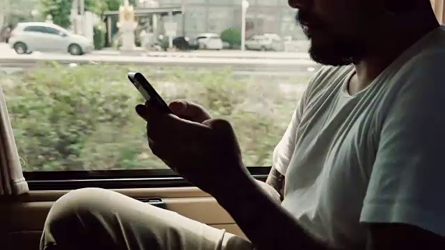 一名亚洲男子在出租车上用智能手机上网视频素材