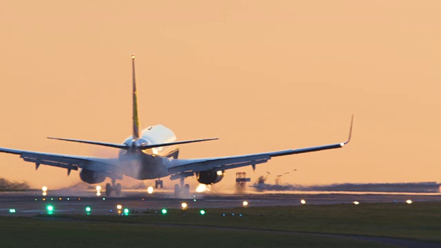 日落时分，一架飞机带着着陆灯降落。视频素材