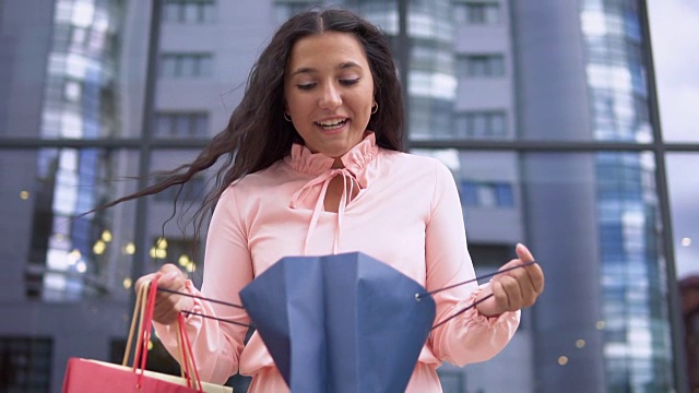 年轻女孩穿着粉红色的衣服购物后，手里拿着包裹有一个好心情。缓慢的运动。高清视频素材