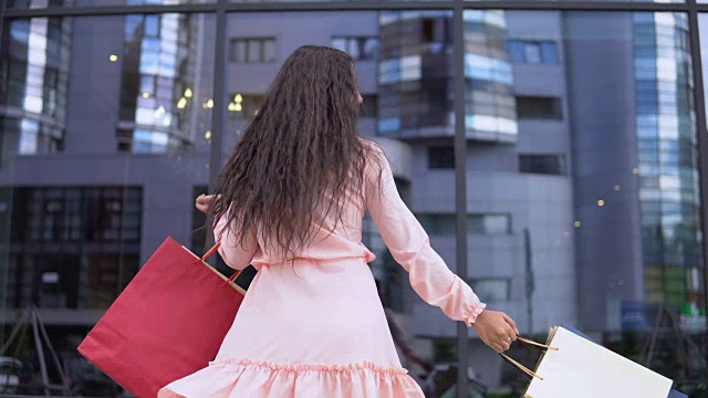 年轻的女孩在购物后摆姿势与包裹在手里。4 k视频素材