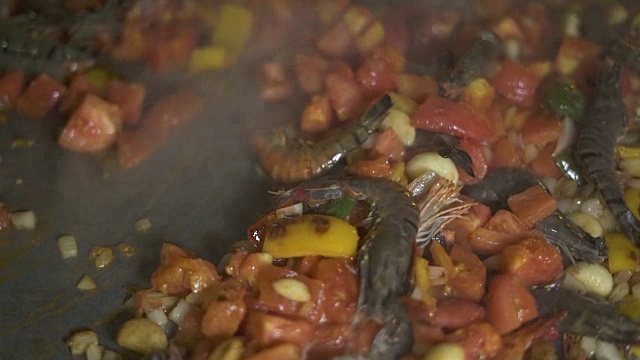 厨师烹饪虾用大蒜和辣椒在锅关闭。在餐厅厨房里制作西班牙菜。用平底锅烹制西班牙海鲜饭的海鲜炖蔬菜视频素材