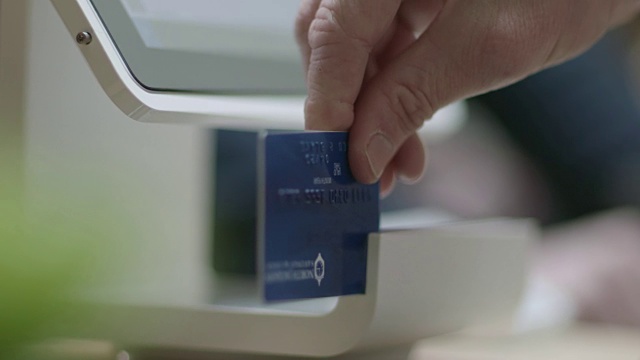 零售工作人员在现代商店的收银台为顾客刷信用卡和旋转平板电脑。视频下载