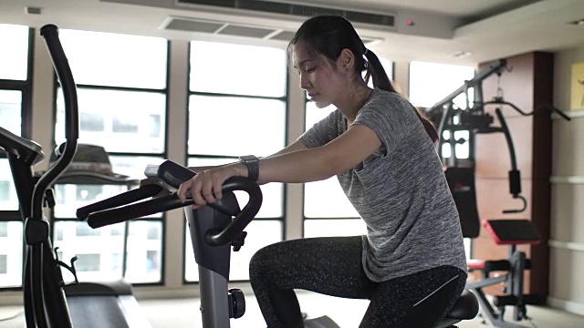 女人在健身房骑自行车视频素材