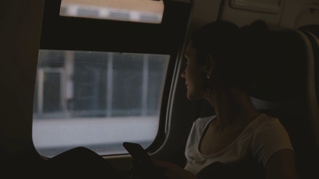 美丽的白人女商人在火车上使用智能手机，打字，看窗户视频购买