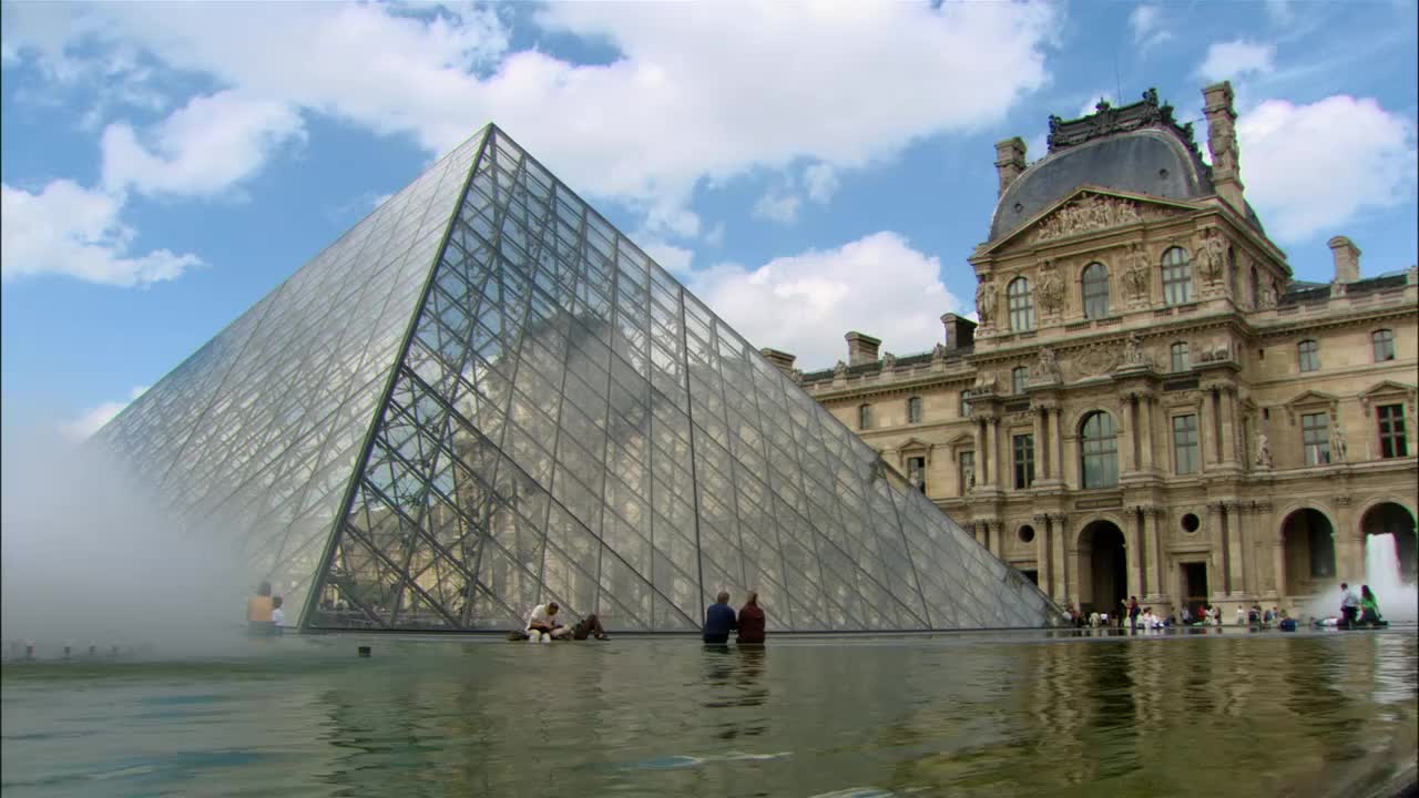 法国巴黎卢浮宫金字塔脚下，人们坐在倒影池旁视频下载