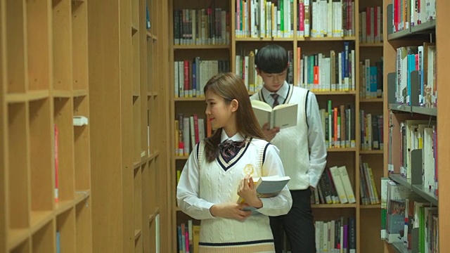一个女学生和一个男学生在图书馆看书视频素材