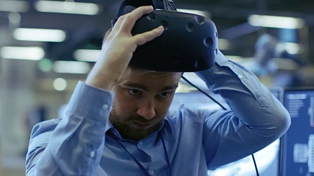 特写肖像的工业工程师戴上虚拟现实耳机，准备工作。在后台制造工厂和监视器。视频下载