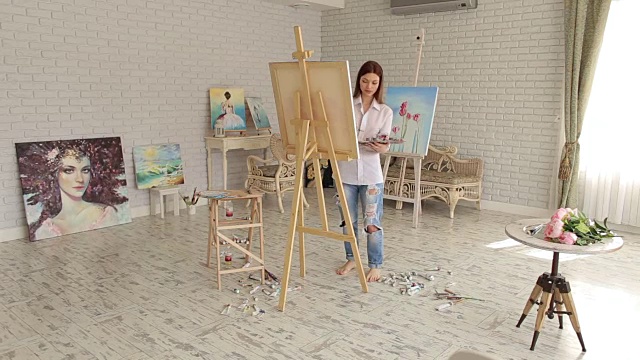 一个富有创造力的年轻女孩在画室里画画。视频素材