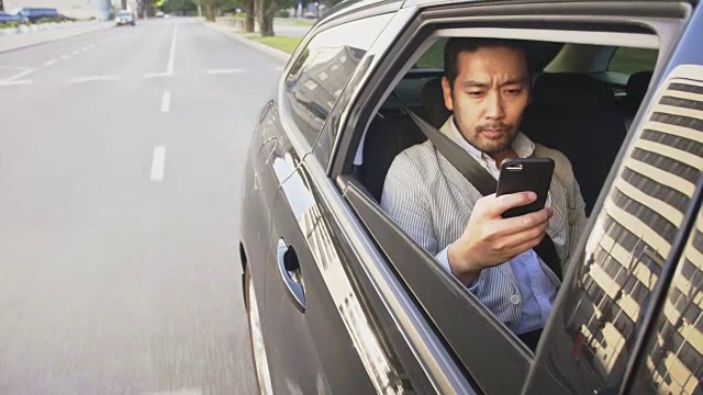 商人在使用智能手机的同时乘坐优步穿越城市视频下载
