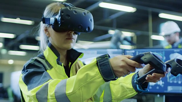 工厂:女工业工程师戴着虚拟现实耳机和手持控制器，她在CAD软件中使用VR技术进行工业设计、开发和原型。视频素材