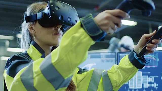 工厂:女工业工程师戴着虚拟现实耳机和手持控制器，她在CAD软件中使用VR技术进行工业设计、开发和原型。视频素材