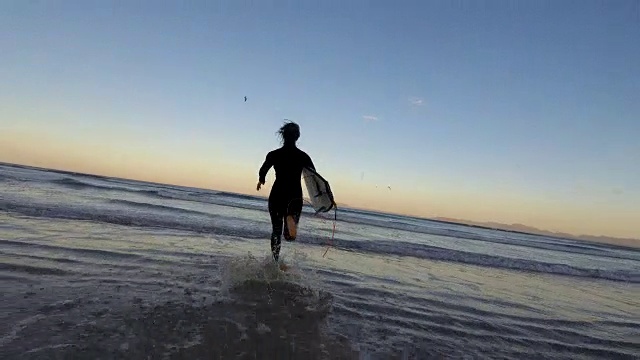 一个女人用她的冲浪板冲进了海浪视频素材