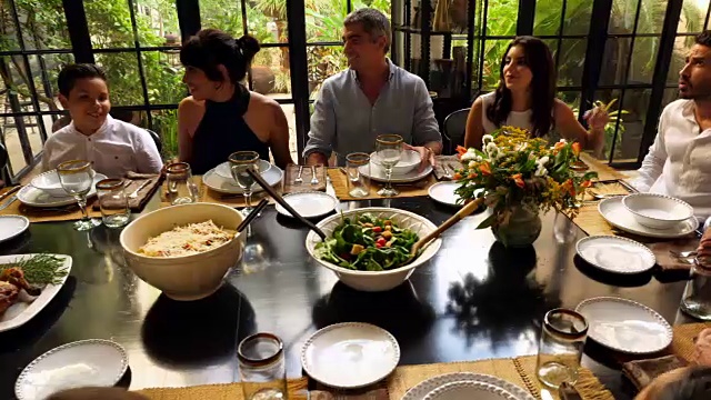 在晚宴上，家人聚在桌子旁微笑着分享食物和故事视频素材