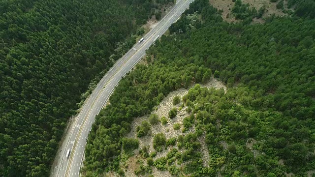 无人机在森林乡村道路上移动的汽车。森林中树木之间的公路航拍镜头视频素材