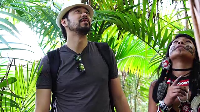 来自瓜拉尼族的土著巴西年轻女子向游客展示热带雨林视频素材