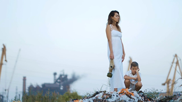 妈妈和儿子。垃圾堆。以工业工厂为背景。环境污染的概念视频素材