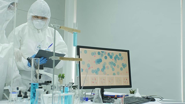 医学研究科学家在安全的高水平研究实验室工作，在计算机上工作，在显微镜下看物质。明亮现代的实验室视频购买
