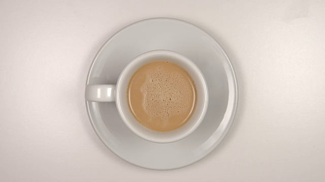 顶视图:喝一杯拿铁咖啡从一个白色的咖啡杯-停止运动视频下载
