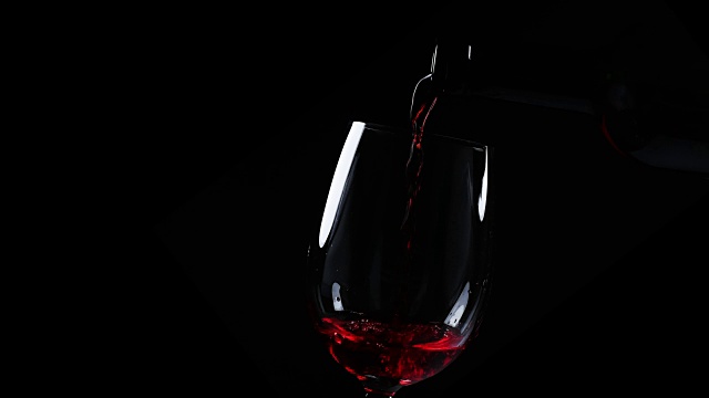 红酒洒在杯子上，黑色，特写慢镜头。视频素材