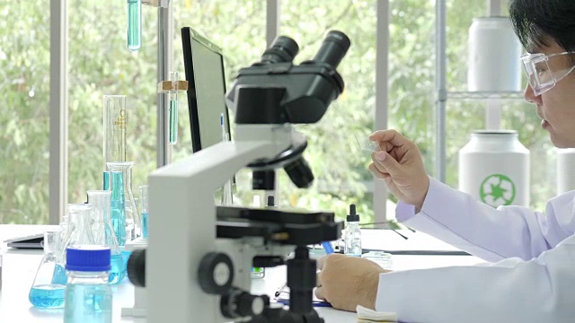 在实验室里通过显微镜观察医学研究的科学家视频购买