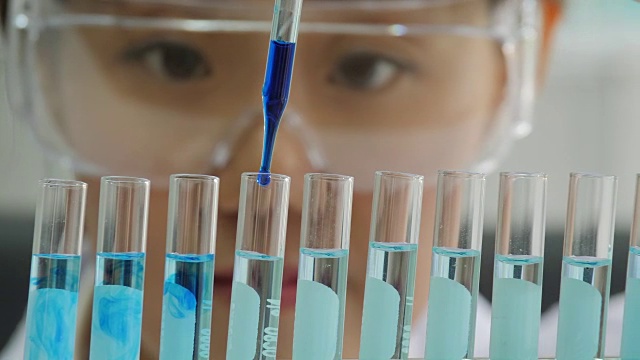 一个科学家用移液管分析有色液体，从试管中提取DNA和分子视频购买