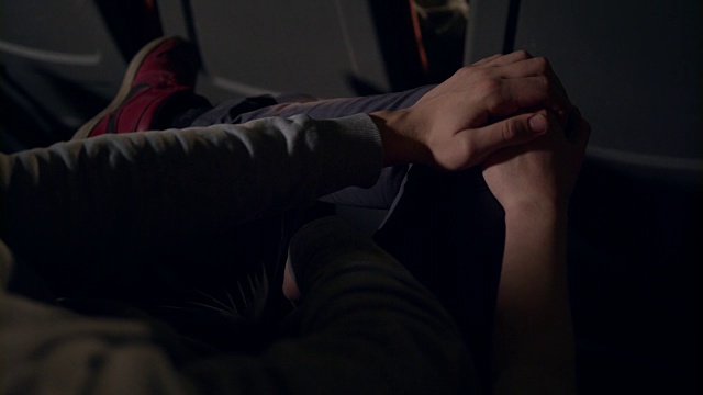 电影院里女人的手抚摸着男人的膝盖。在电影院牵手的夫妇视频素材