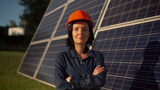戴着橙色头盔的女子站在太阳能电池板旁视频下载