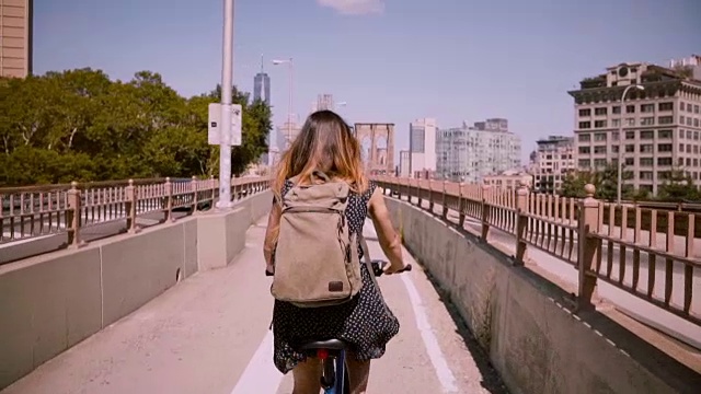后景快乐的女孩与飞扬的黑发骑自行车沿着一个单独的自行车道在纽约慢镜头视频素材