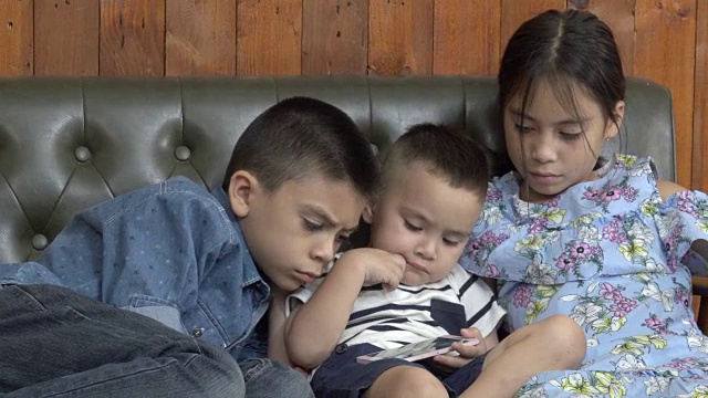 三个兄弟姐妹在看智能手机视频素材