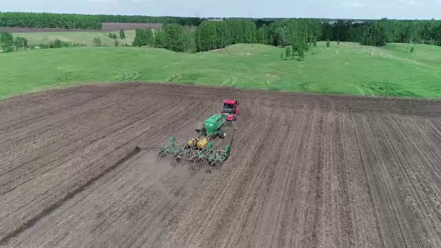 鸟瞰图的拖拉机与一个播种机通过田地视频下载