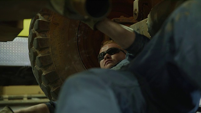 靠近的机械师躺在卡车和移除消声器锤/极光，犹他州，美国视频素材
