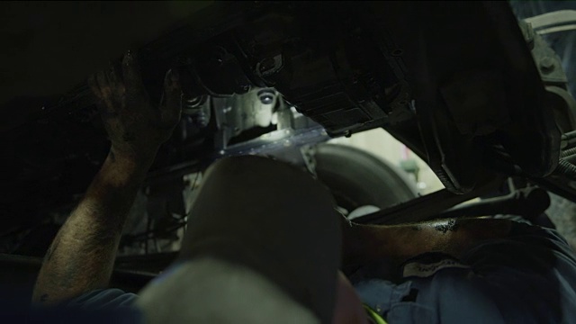 使用手电筒/美国犹他州奥罗拉，近距离观察机械师躺在卡车下的低角度视频素材