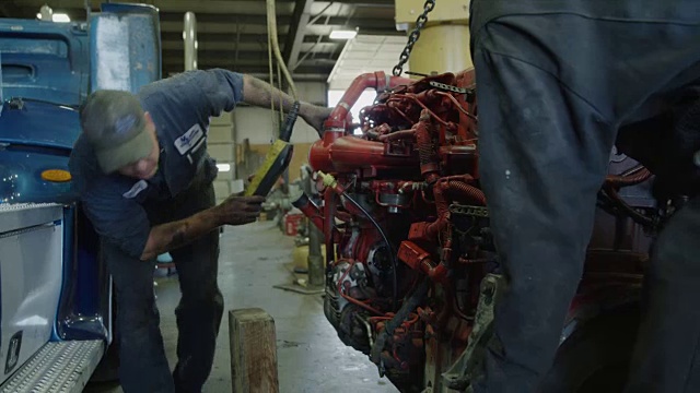 在美国犹他州奥罗拉的车库，机械师在卡车引擎下面布置块视频素材