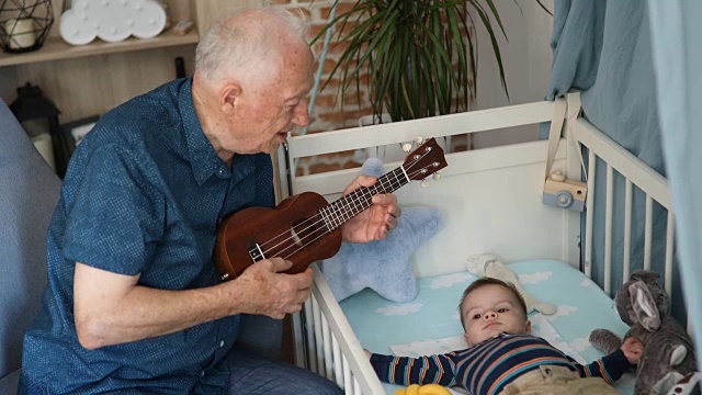 爷爷在给孙子弹奏四弦琴视频素材