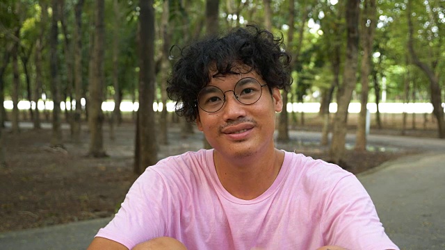 快乐的亚洲英俊的年轻男子的肖像照相机城市公园。视频素材