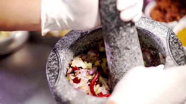 厨师用花岗岩研钵和研杵捣碎混合香料和药草原料，制作泰国菜。视频素材