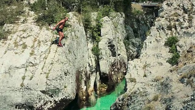 一名男子从岩石上跳入清澈的水中视频下载