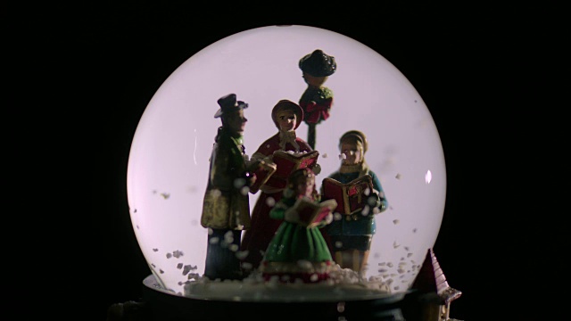 雪花停止在一个雪球里的塑料颂歌歌手周围飘落。视频下载
