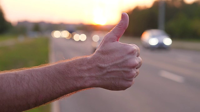 男人把手举起大拇指，搭车人在路上试图赶上汽车视频下载
