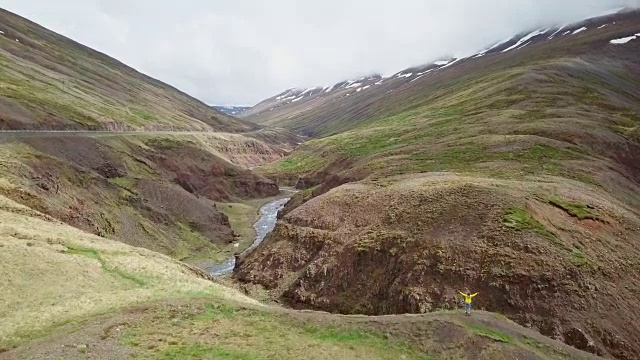 一名女子伸开双臂站在冰岛峡谷顶上的无人机照片令人惊叹视频素材
