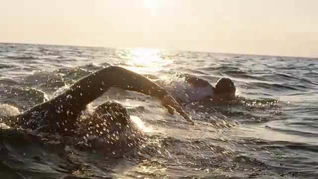 两名公开水域游泳者在阳光下的波涛汹涌的海面上游泳视频素材