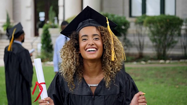 一位女毕业生对着镜头微笑，兴奋地欢呼视频下载