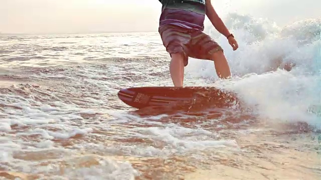 一个人在日落时在慢镜头中冲浪的特写。水极限运动。视频素材